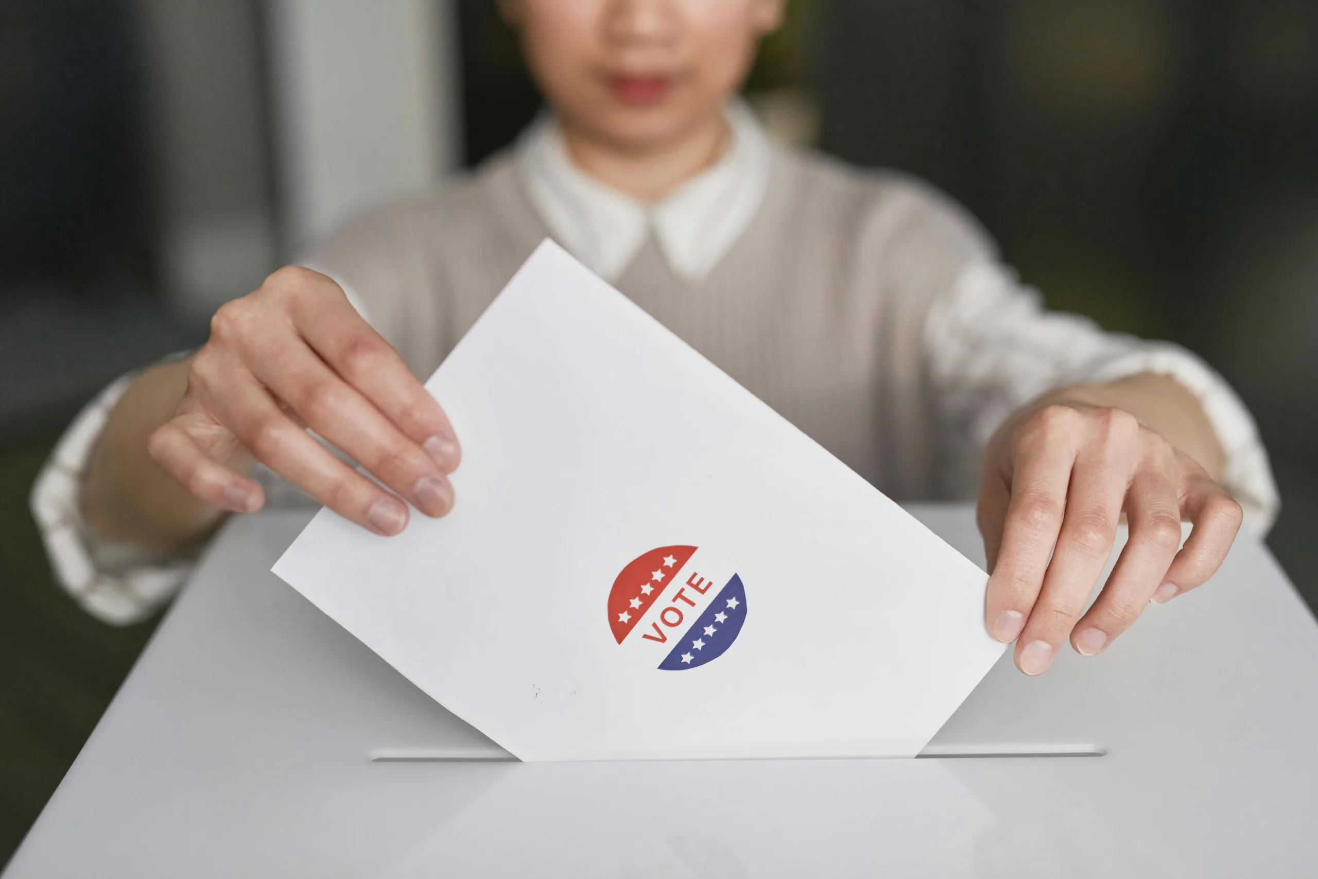 Service de Dropshipping 5 A person casting a vote by placing a ballot into a ballot box, symbolizing democratic participation.