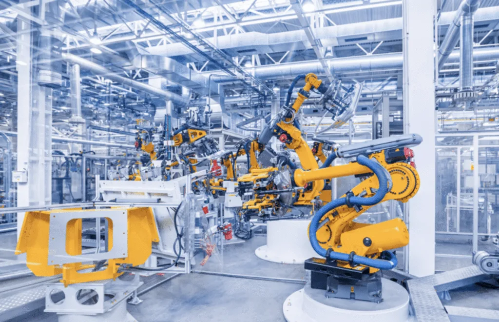 Industrial robotic arms operating inside a high-tech automated manufacturing line with interconnected machinery and metal components.