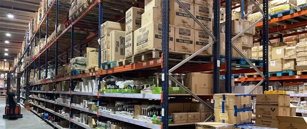 Large warehouse interior with tall industrial shelving units filled with boxed products and palletized inventory organized for logistics and distribution.