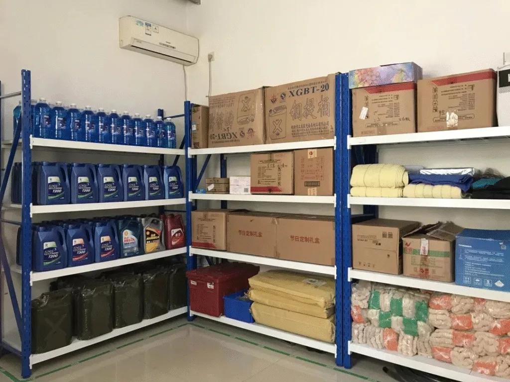 Indoor storage room with blue metal shelving holding boxed goods, bottled liquids, containers, and folded supplies neatly organized.